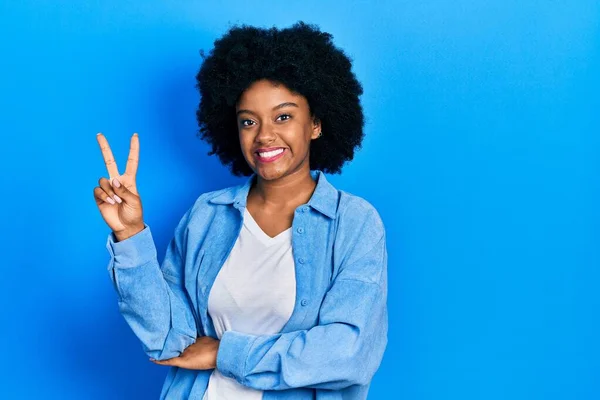 若いアフリカ系アメリカ人の女性は 勝利のサインを行う指を示すカメラを見て笑顔カジュアルな服を着ています — ストック写真