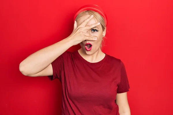 Young Blonde Woman Wearing Casual Red Shirt Peeking Shock Covering — Stockfoto