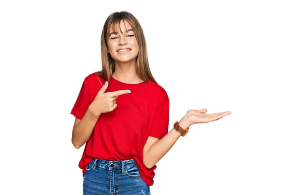 十代の若いですCaucasian女の子身に着けていますカジュアル赤Tシャツ驚きと笑顔にカメラに提示しながら手と指差し指 — ストック写真