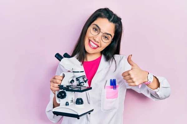 Young Hispanic Girl Wearing Scientist Uniform Holding Microscope Smiling Happy — Zdjęcie stockowe