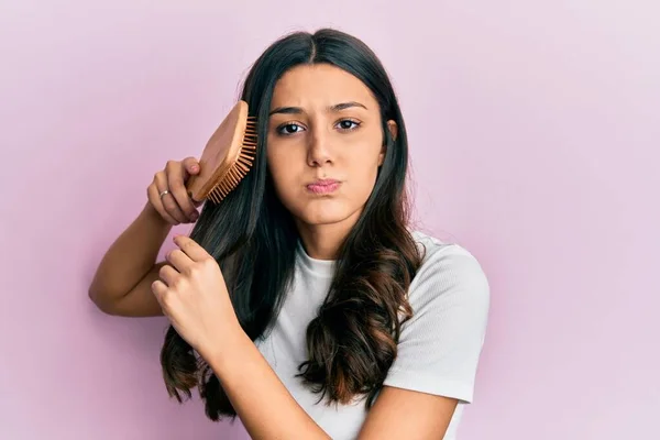 Young Hispanic Woman Styling Hair Using Comb Puffing Cheeks Funny — Stockfoto