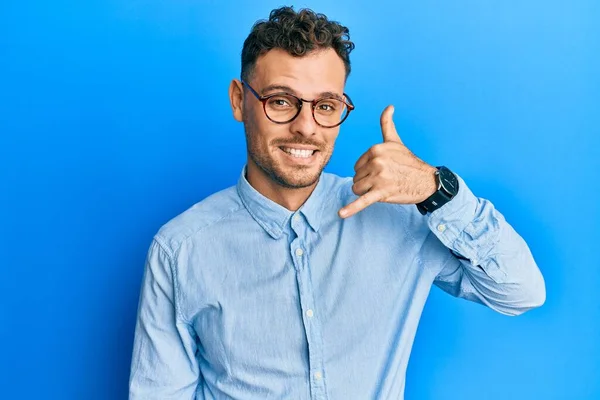 若いヒスパニック系の男性がカジュアルな服を着て 眼鏡を手や指で電話で話をするような携帯電話のジェスチャーを行う笑顔 コミュニケーションの概念 — ストック写真