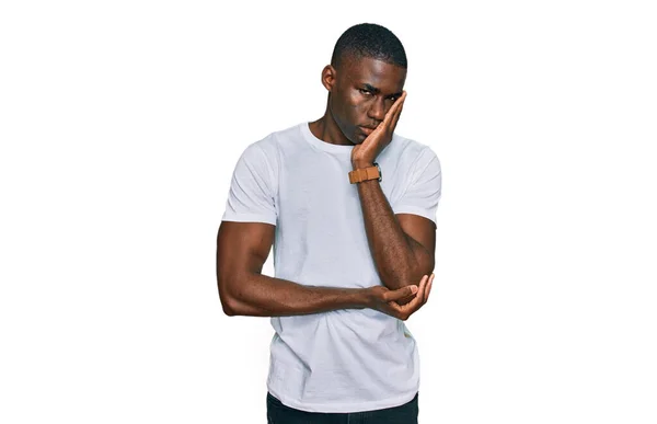 若いですアフリカ系アメリカ人男性身に着けていますカジュアルホワイトTシャツ思考疲れていると退屈でうつ病問題で交差腕 — ストック写真