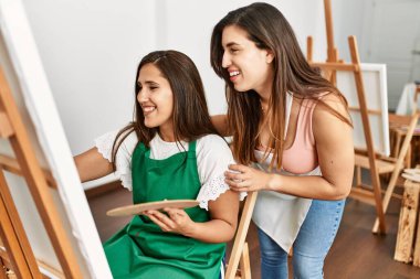 Öğrenci ve öğretmen resim yaparken gülümsüyor..