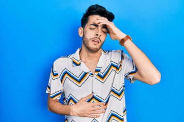 Günlük kıyafetler giyen genç İspanyol adam hastalık, ateş, grip ve virüs için alnına dokunuyor. 