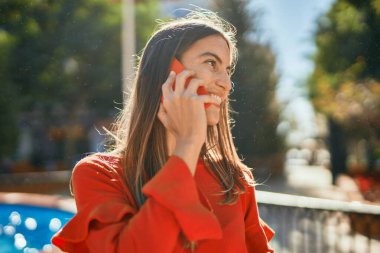 Genç İspanyol kadın gülümsüyor. Şehirdeki akıllı telefondan konuşuyor..