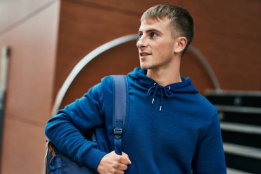 Üniversitede mutlu bir şekilde gülümseyen genç sarışın öğrenci..