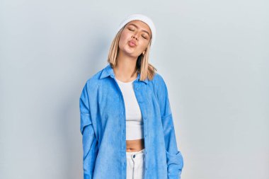 Güzel sarışın kadın, yün şapka takmış kameraya bakıyor ve güzel ve seksi bir şekilde havadan öpücük yolluyor. aşk ifadesi. 