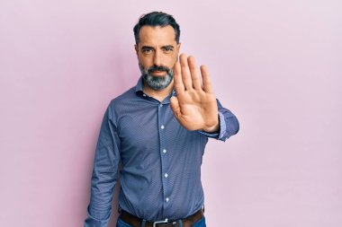 Orta yaşlı, sakallı, gri saçlı iş kıyafetleri giyen bir adam avucunun içi gibi şarkı söylemeyi kesiyor. Yüzünde olumsuz ve ciddi bir jest olan uyarı ifadesi. 