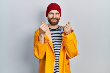 Sakallı, sarı yağmurluk giyen, elleriyle para hareketi yapan, maaşını isteyen, milyonerlik işi yapan beyaz bir adam. 