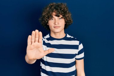 Sıradan çizgili tişört giyen yakışıklı genç adam avucunun içi gibi şarkı söylemeyi kesiyor. Yüzünde olumsuz ve ciddi bir jest olan uyarı ifadesi. 