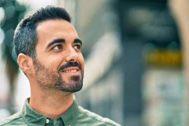 Genç İspanyol adam gülümseyerek şehirde mutlu mesut dikiliyor..