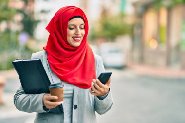 Genç Arap iş kadını akıllı telefon kullanıyor ve şehirde kahve içiyor..