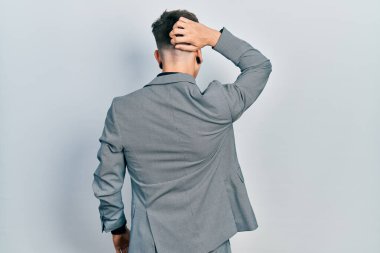 Kulakları büyümüş, iş ceketini ters giymiş, elleri kafasında şüpheyi düşünen beyaz bir çocuk. 