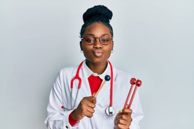 Genç Afro-Amerikan kadın doktor üniforması giymiş elinde çatal tutarak kameraya bakıyor öpüşme sahnesini çekiyor. Sevimli ve seksi. aşk ifadesi. 