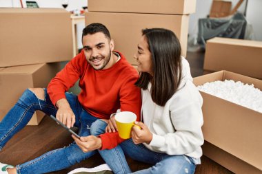 Genç Latin çift kahve içiyor ve yeni evlerinde dokunmatik ped kullanıyor..