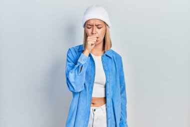 Yün şapka takan güzel sarışın kadın kendini iyi hissetmiyor ve soğuk algınlığı veya bronşitin belirtisi olarak öksürüyor. sağlık hizmeti kavramı. 