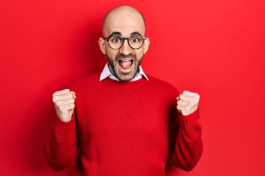 Gündelik kıyafetler giyen ve gözlük takan genç kel adam, başarı için şaşırmış ve hayrete düşmüştü. Kolları havada ve gözleri açıktı. Kazanan konsept. 