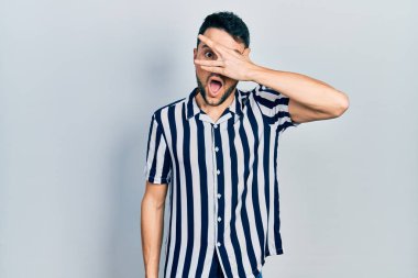 Gündelik kıyafetler giyen genç İspanyol adam şok içinde yüzünü ve gözlerini kapayarak utanmış ifadesiyle parmaklarından bakıyor.. 