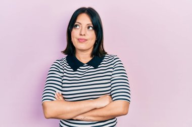 Kollarını kavuşturmuş, gülümseyen, yan bakıp düşünen İspanyol bir kadın.. 