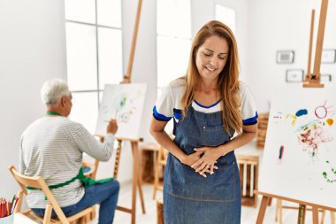 Resim stüdyosunda önlük giyen İspanyol bir kadın midesi üstünde, çünkü hazımsızlık, acı verici bir hastalık kendini iyi hissetmiyor. Ağrı kavramı. 