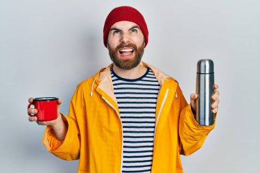 Kafkas sakallı bir adam elinde kahve fincanı ve termo kızgın ve kızgın çığlıklar sinirli ve öfkeliydi. Öfkeyle bağırıyordu.. 