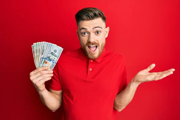 Young Redhead Man Holding Dollars Celebrating Achievement Happy Smile Winner —  Fotos de Stock