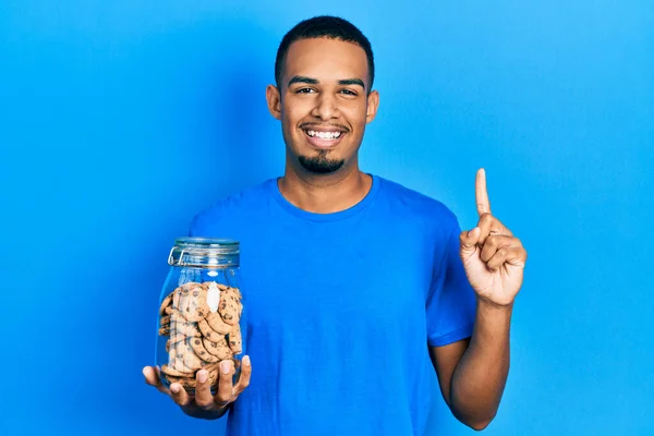 Joven Hombre Afroamericano Sosteniendo Tarro Galletas Chispas Chocolate Sonriendo Con — Foto de Stock