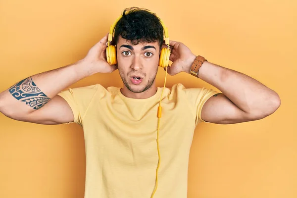 Joven Hispano Escuchando Música Usando Auriculares Con Cara Shock Escéptico — Foto de Stock