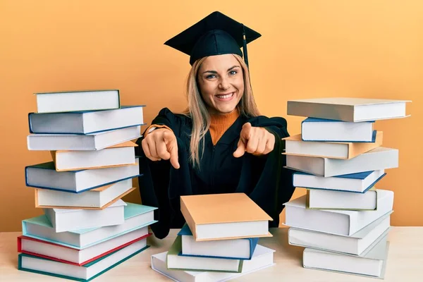 Young Caucasian Woman Wearing Graduation Ceremony Robe Sitting Table Pointing —  Fotos de Stock