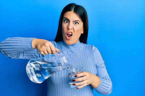 Vacker Brunett Kvinna Hälla Vatten Glas Chock Ansikte Ser Skeptisk — Stockfoto