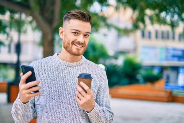 Νεαρός Καυκάσιος Άνδρας Που Χρησιμοποιεί Smartphone Πίνοντας Καφέ Στο Πάρκο — Φωτογραφία Αρχείου