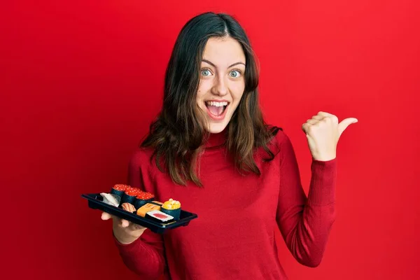 Jovem Morena Mostrando Uma Placa Sushi Apontando Polegar Para Lado — Fotografia de Stock