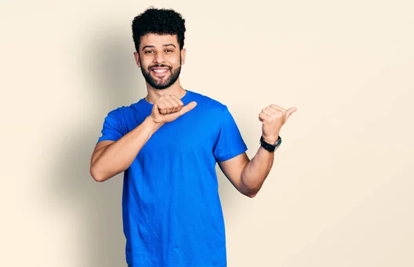 年轻的阿拉伯男子 留着胡子 穿着休闲的蓝色T恤 手背朝后 竖起大拇指 带着自信的微笑 — 图库照片