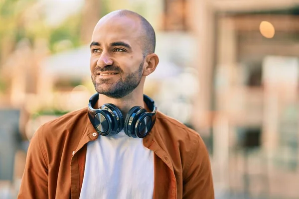 Young hispanic bald man smiling happy using headphones at the city