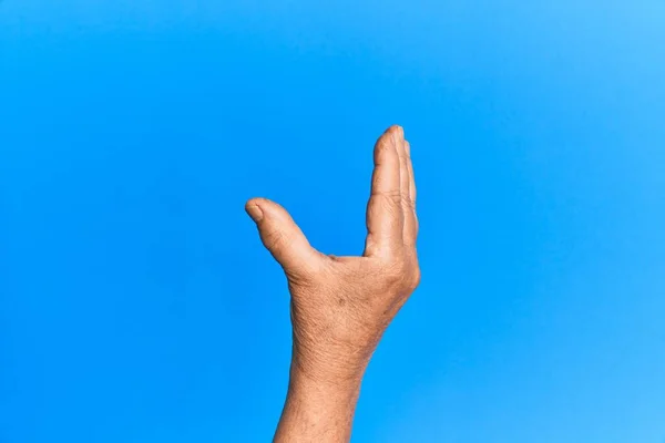 Mão Homem Hispânico Sênior Sobre Azul Isolado Fundo Pegar Tomar — Fotografia de Stock