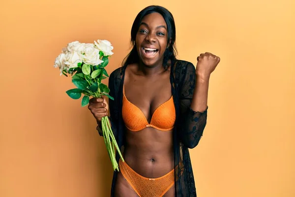 Νεαρή Αφροαμερικανή Γυναίκα Φορώντας Εσώρουχα Κρατώντας Λουλούδια Ουρλιάζοντας Περήφανη Γιορτάζοντας — Φωτογραφία Αρχείου