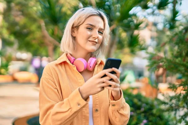 Parkta Akıllı Telefon Kulaklık Kullanarak Gülümseyen Genç Sarışın Kız — Stok fotoğraf