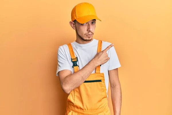 Hispanic Young Man Wearing Handyman Uniform Pointing Hand Finger Side — 图库照片