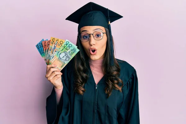 Young Hispanic Woman Wearing Graduation Uniform Holding Australian Dollars Scared — Stock Photo, Image