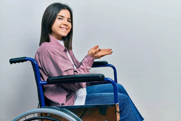 Young Brunette Woman Sitting Wheelchair Pointing Aside Hands Open Palms — Foto de Stock