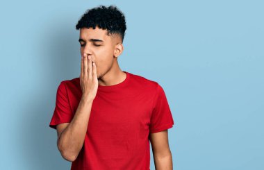 Genç Afro-Amerikalı bir adam günlük kırmızı t-shirt giymekten sıkılmış, ağzını eliyle kapatmaktan sıkılmış. Huzursuz ve uykulu.. 