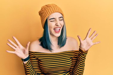 Yün şapka takan genç bir kız başarının çılgınlığını kutluyor. Kollarını kaldırmış, gözlerini kapatmış heyecanla bağırıyor. Kazanan konsept 