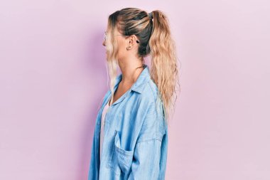 Güzel, genç, sarışın bir kadın, günlük kıyafetler ve gözlük takıyor, yan tarafa bakıyor, rahat poz veriyor, kendine güvenen bir gülümsemeyle doğal bir yüz ifadesi sergiliyor.. 