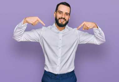 Sakallı, iş gömleği giyen, kendine güvenen, gülümseyen, kendini gururlu ve mutlu gösteren genç bir adam.. 