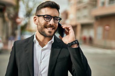Genç İspanyol işadamı gülümsüyor. Şehirdeki akıllı telefondan mutlu bir şekilde konuşuyor..