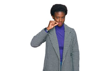 Sıradan kıyafetler giyen, ağzı ve dudakları parmaklarıyla kapanan Afro-Amerikalı genç bir kız. gizli ve sessiz, tabu konuşması 