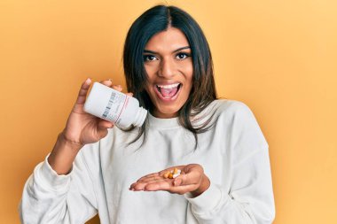 Genç Latin transseksüel kadın elinde haplarla kutlama yapıyor. Çılgınlık ve başarı için hayrete düşmüş. Gözleri açık, heyecanlı çığlıklar atıyor.. 