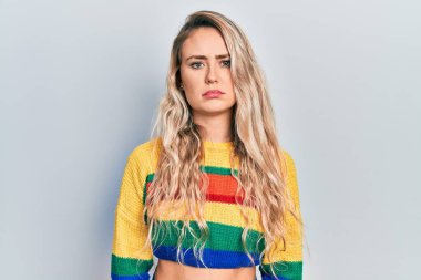 Renkli kazak giyen genç ve güzel sarışın kadın depresyonda ve üzüntüden endişeli, kızgın ve korkmuş bir şekilde ağlıyor. hüzünlü ifade. 