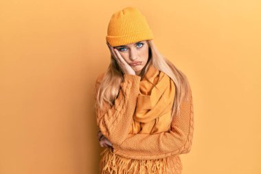 Kafkasyalı genç bir kadın yün kazak ve şapka giyip kollarını kavuşturarak depresyondan sıkılmış ve yorgun görünüyor.. 